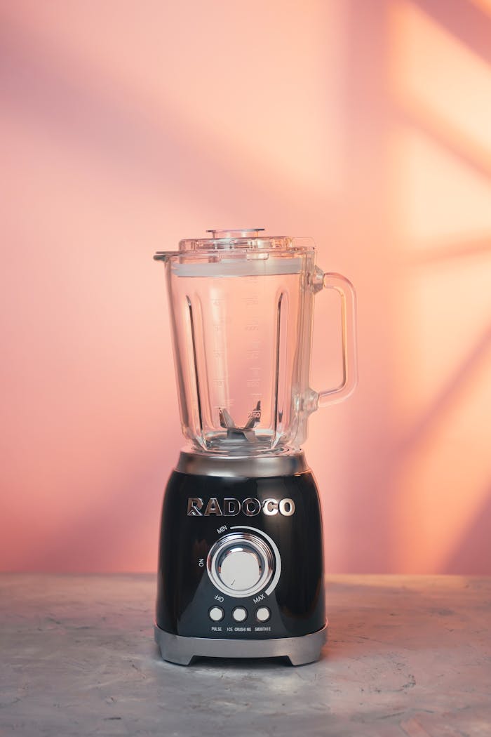 why-choose-us Black blender on a marble surface with a pink background, perfect for modern kitchens.