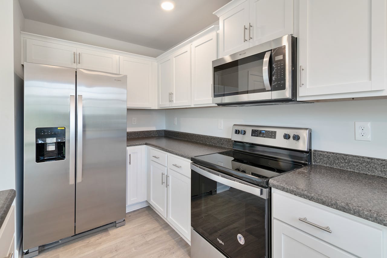 digital Sleek kitchen with stainless steel appliances and white cabinetry.
