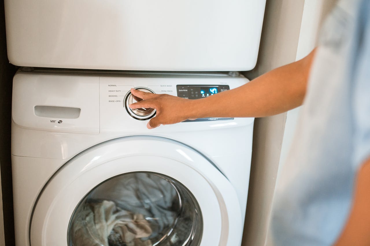 creative-03 Close-up of a person adjusting a washing machine in a modern laundry room.