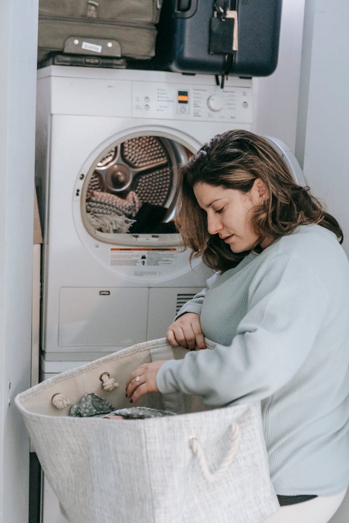 brand-01 A woman engaged in household chores, loading a washing machine with laundry.